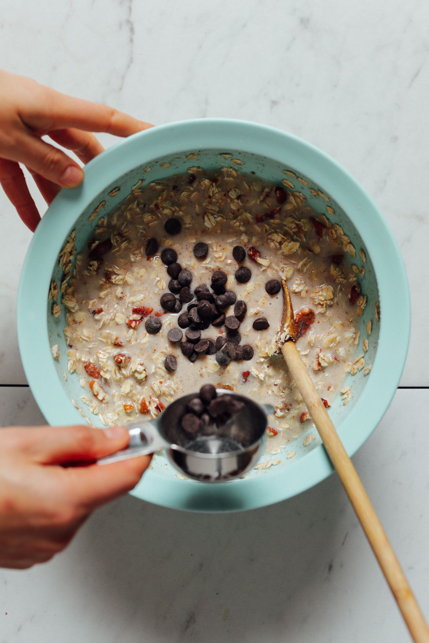 Overhead image of banana oatmeal in a blue bowl with chocolate chips being sprinkled on top
