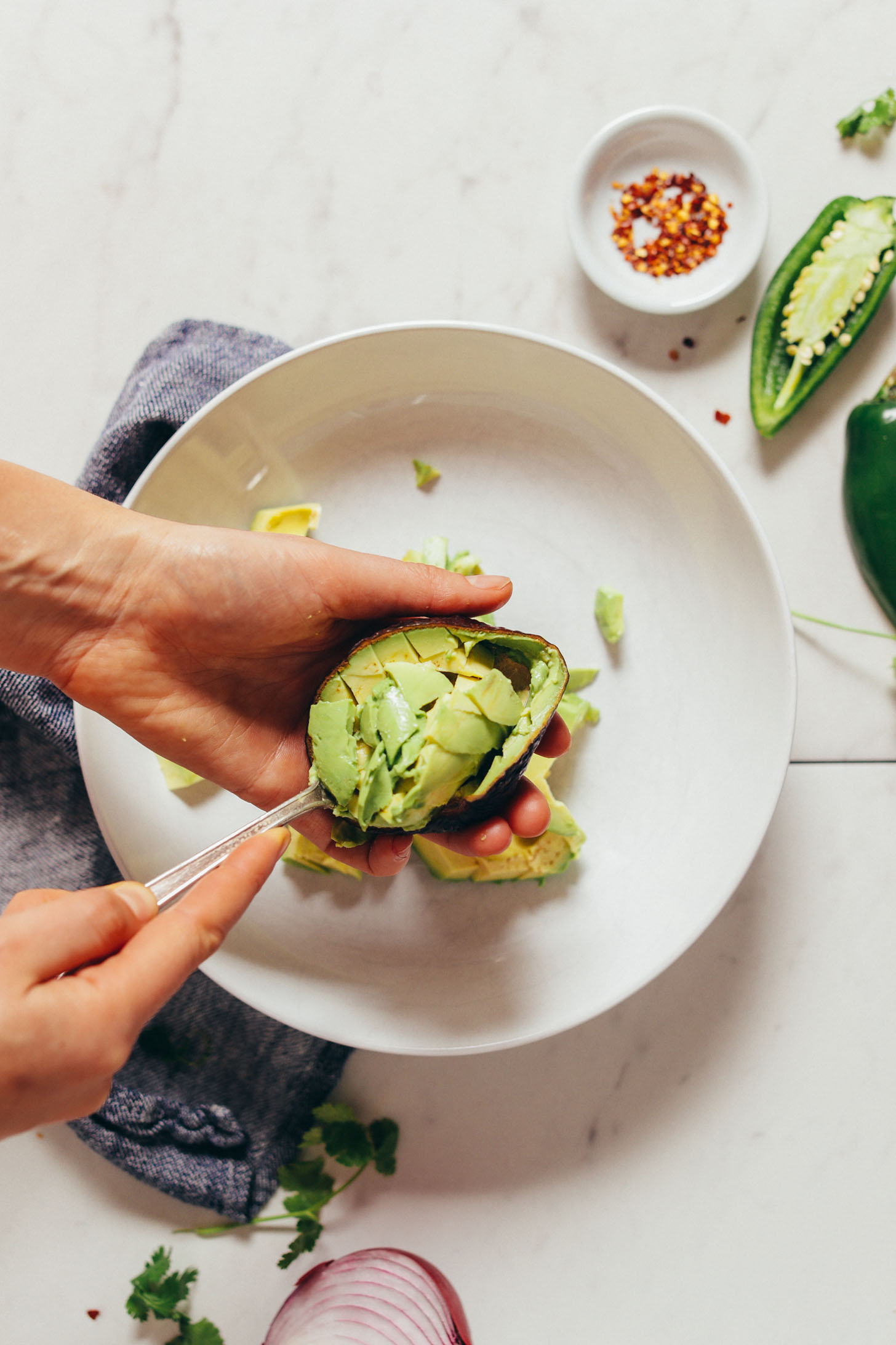 Overhead image of avocado being scooped into a white bowl