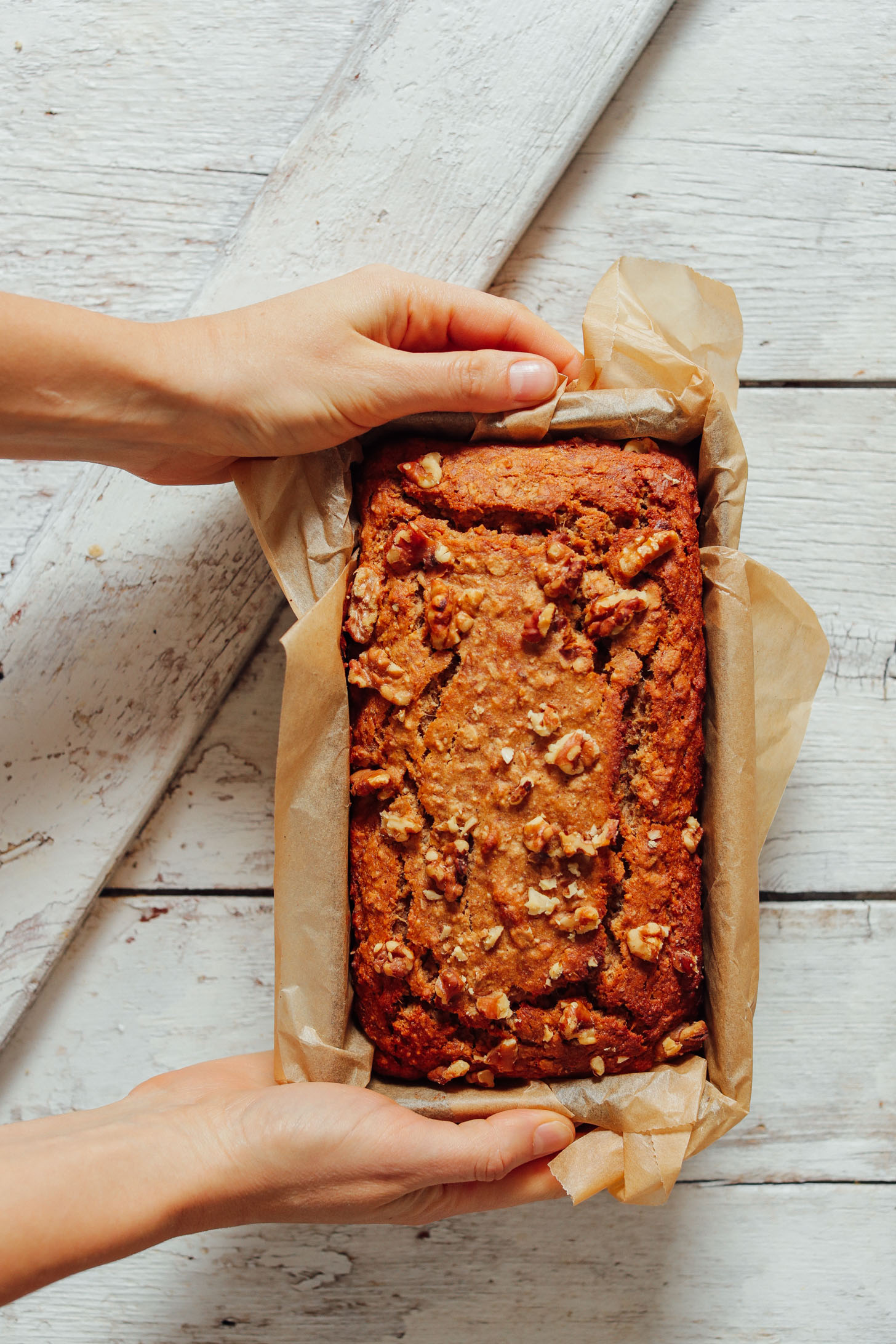 Image of hands holding a loaf of freshly baked banana bread