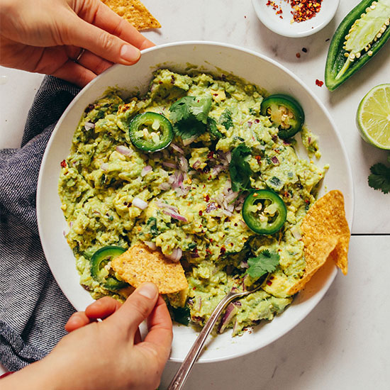 Using a tortilla chip to scoop up a bite of My Go-To Guacamole recipe