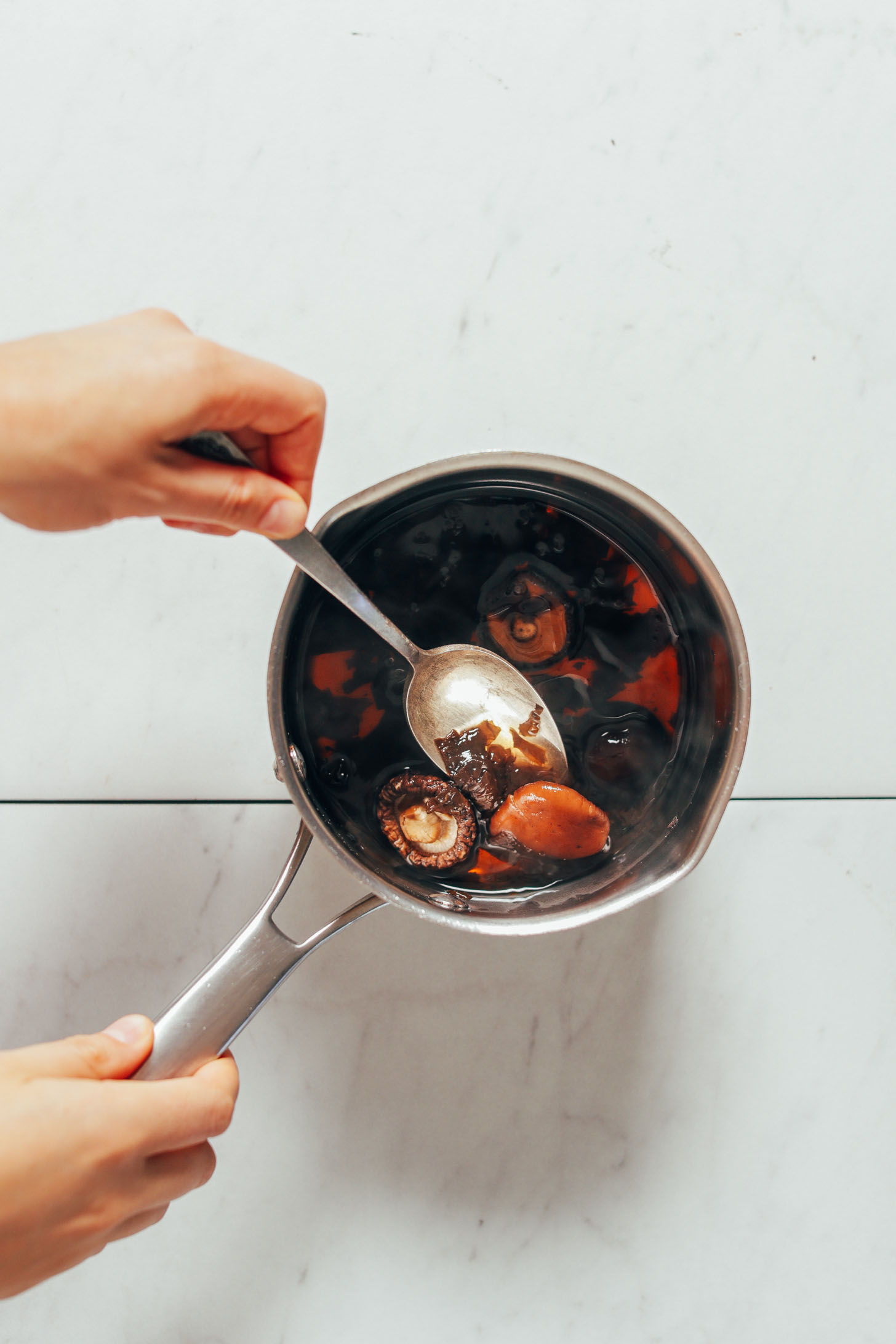 Using a spoon to mix a saucepan with ingredients for our vegetarian Fish Sauce recipe