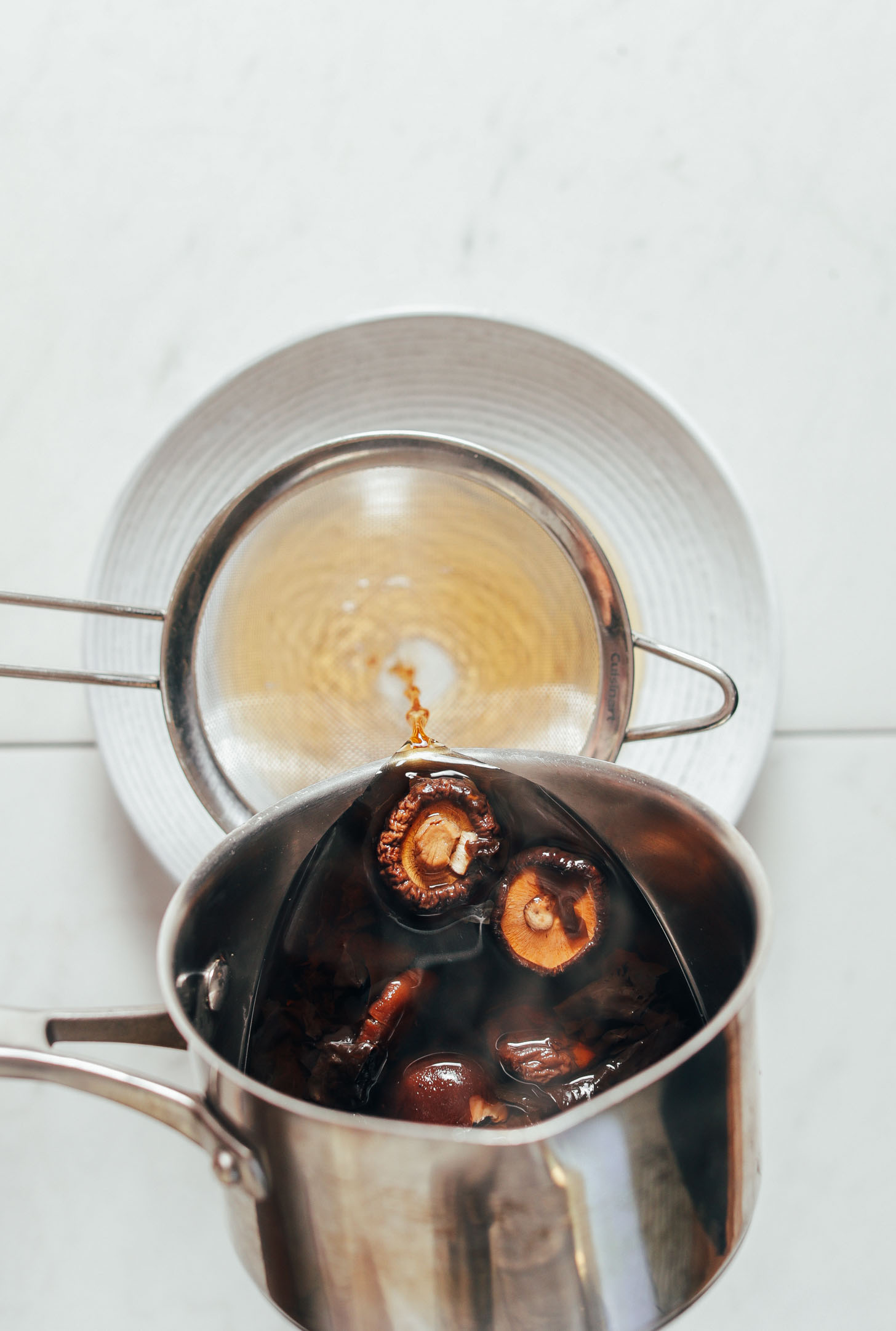 Pouring vegan Fish Sauce ingredients through a fine mesh strainer