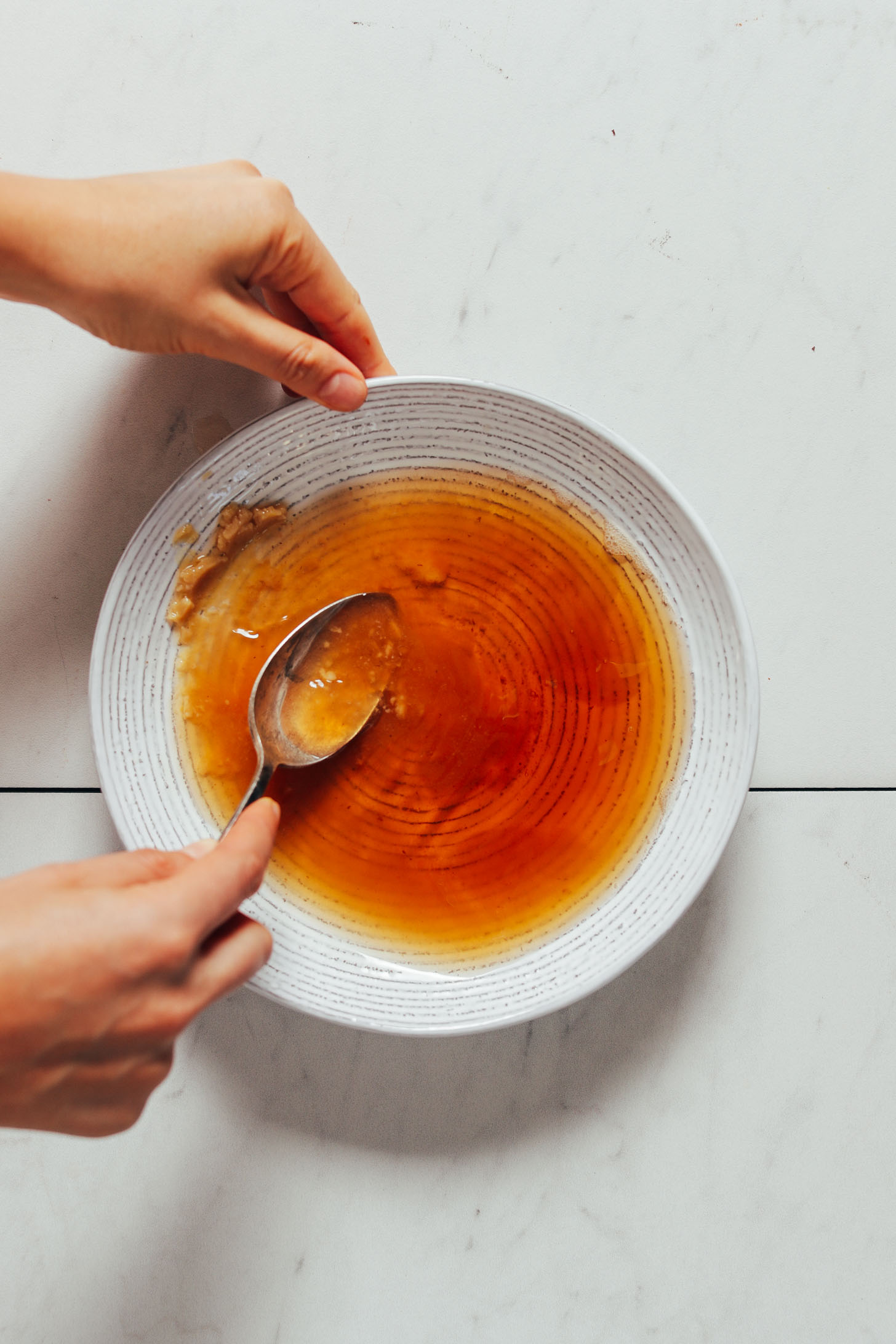 Stirring miso paste in a bowl to make the perfect vegan fish sauce for Thai dishes