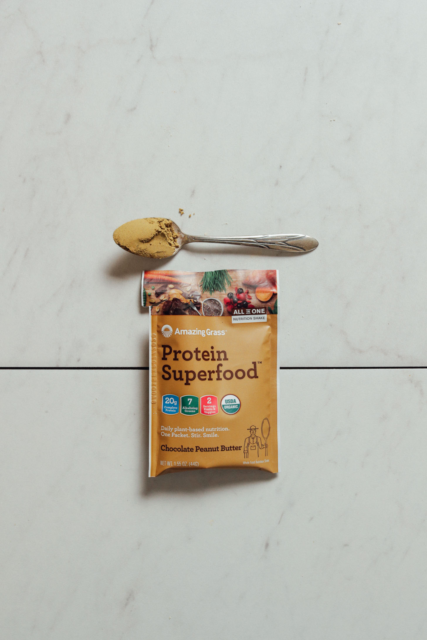 Pouch and spoonful of Amazing Grass Chocolate Peanut Butter Protein Powder for our review