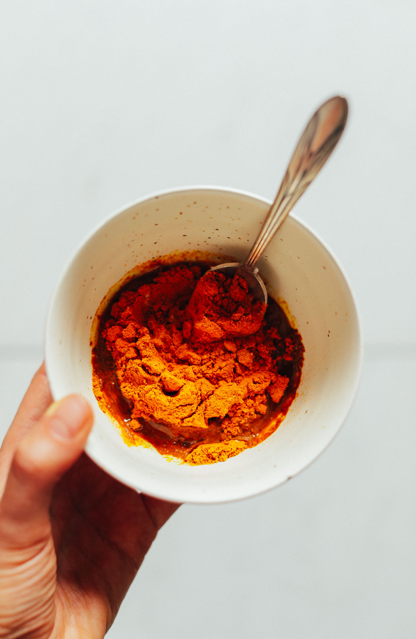 Bowl of spices, coconut oil, and maple syrup for making vegan golden milk paste