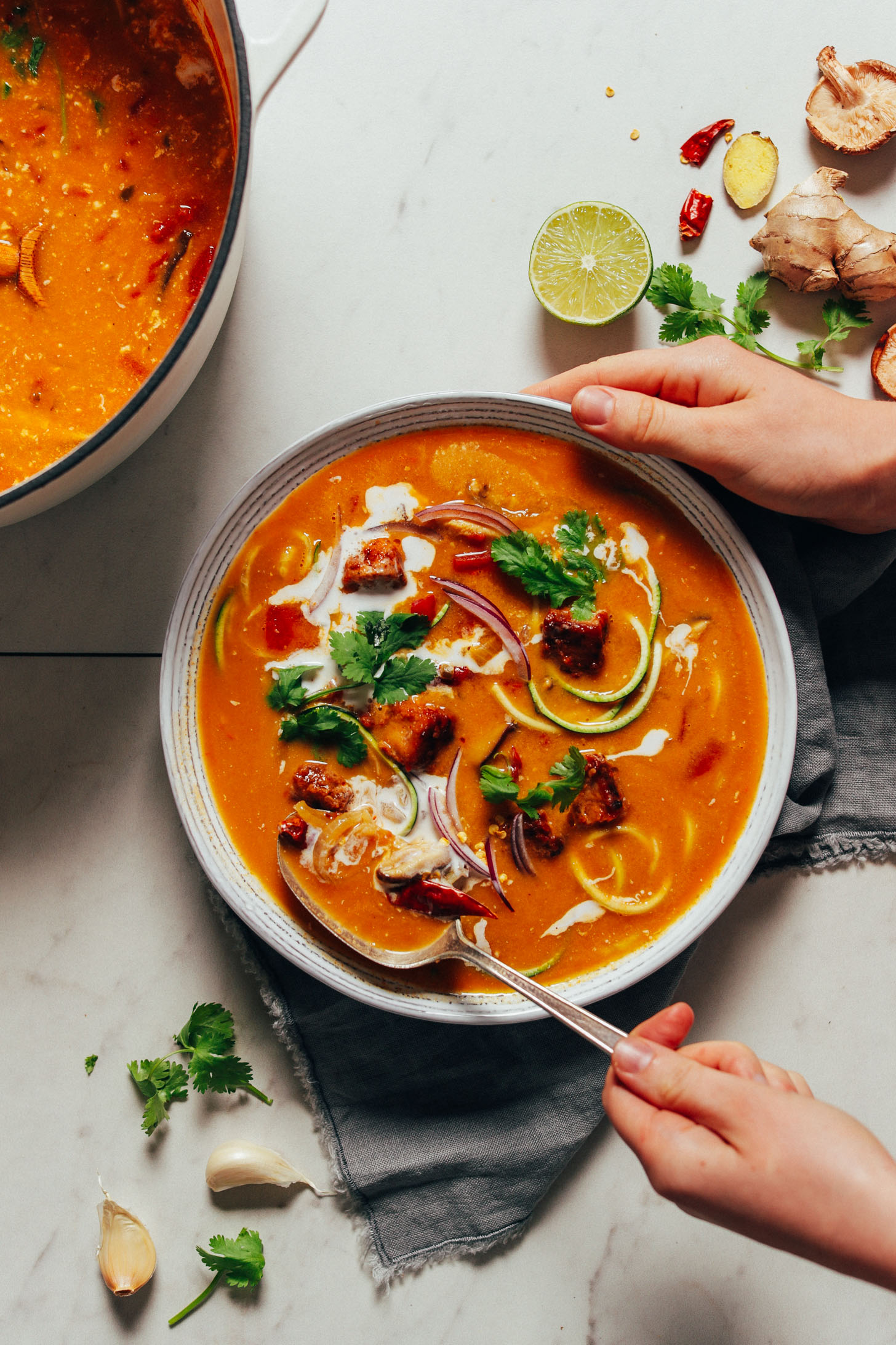 Holding a bowl of nourishing vegan Tom Yum soup