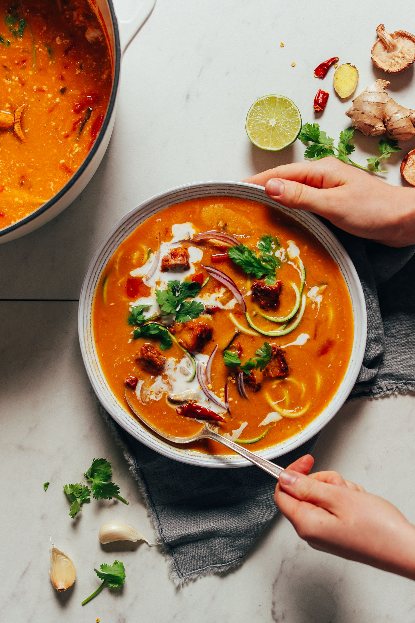 Grabbing a spoonful of our gluten-free Vegan Tom Yum Soup recipe