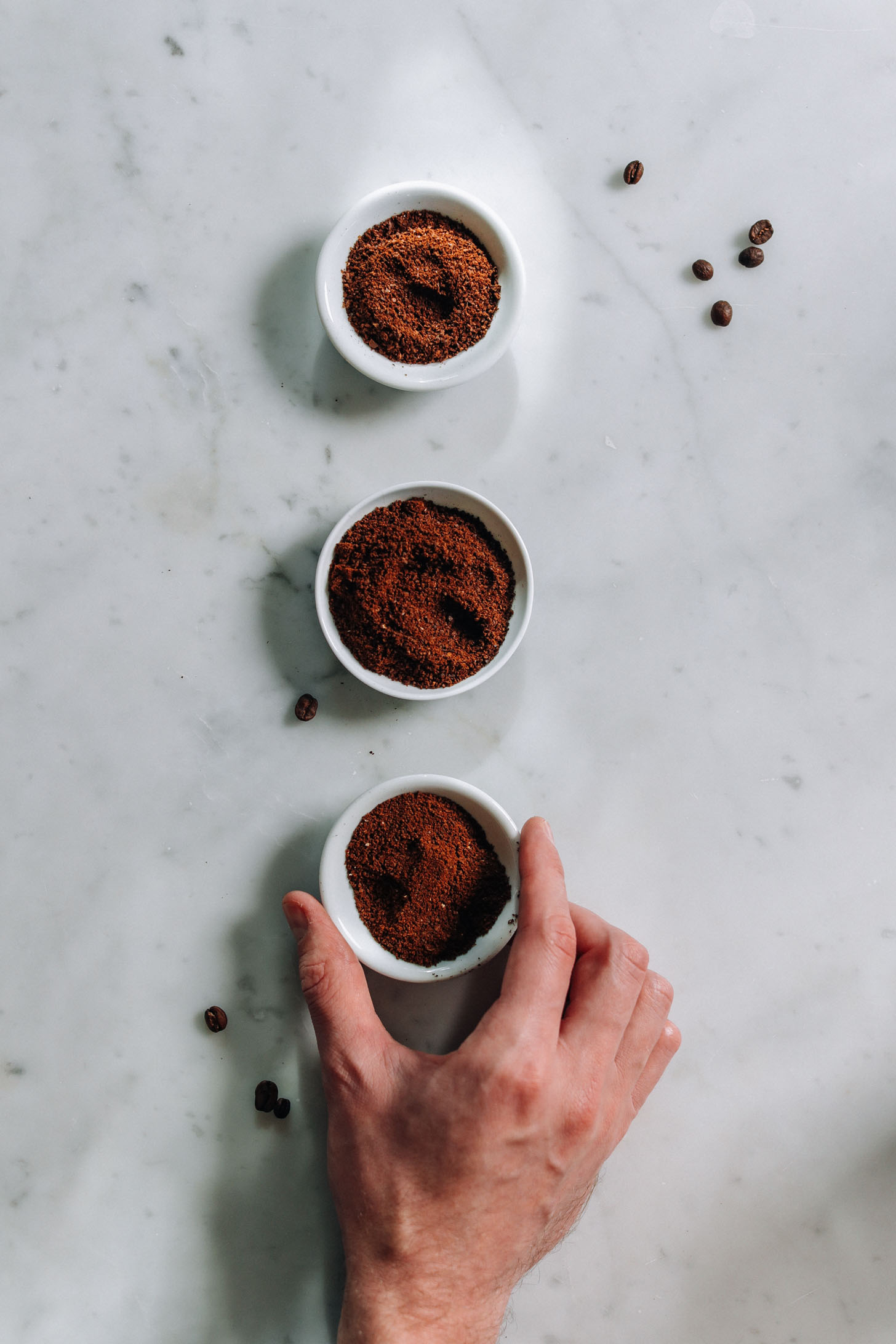 Three small dishes with ground coffee in them