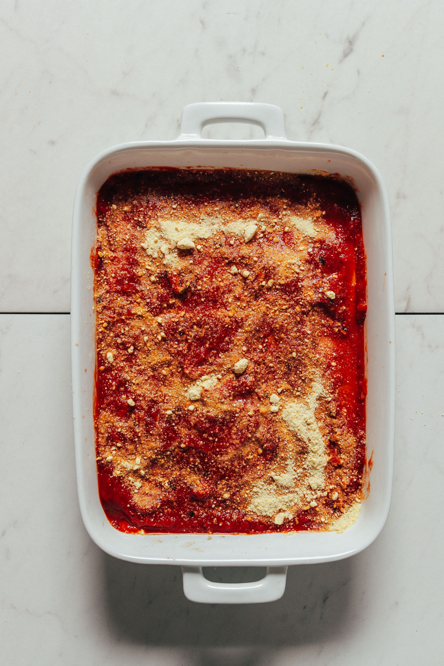 Ceramic baking pan filled with a batch of our Easy Vegan Lasagna topped with Vegan Parmesan