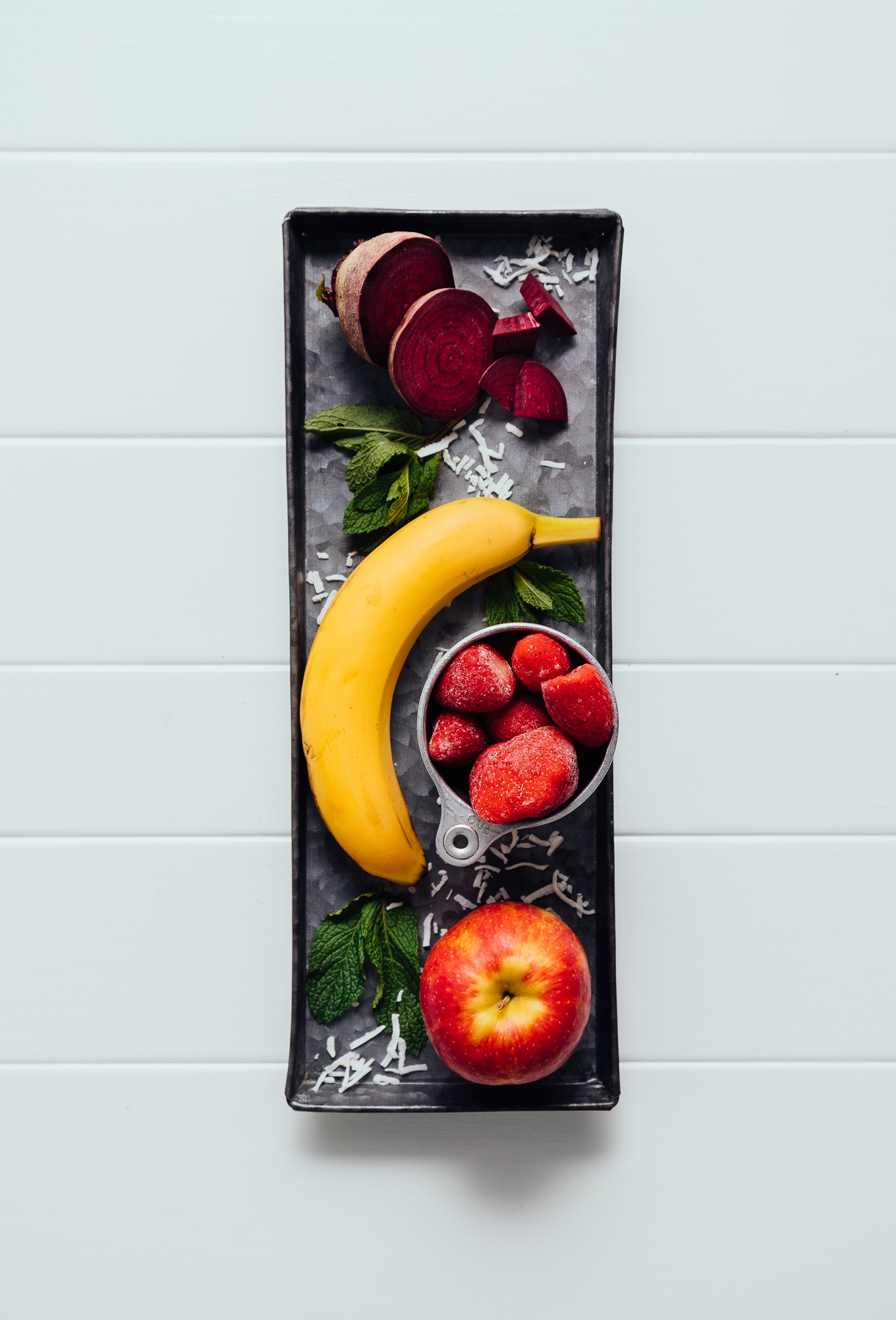 Tray with coconut, mint, apple, strawberries, banana, and beet for making a healthy vegan smoothie recipe