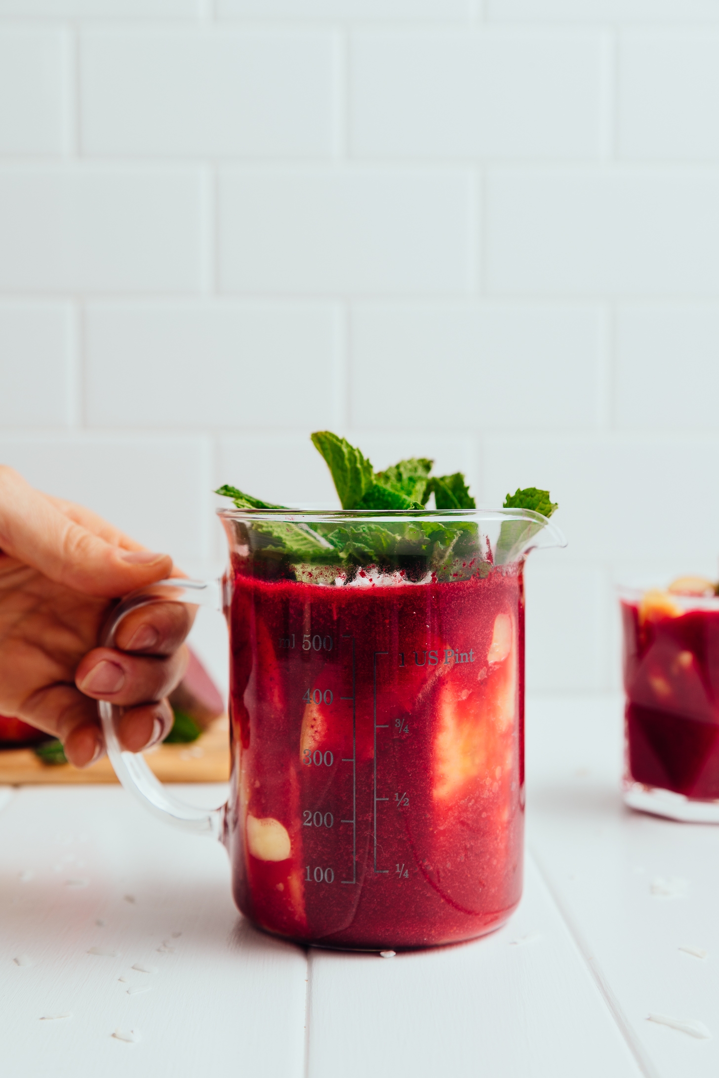 Holding the handle of a measuring glass filled with our Detoxifying Beet and Berry Smoothie recipe