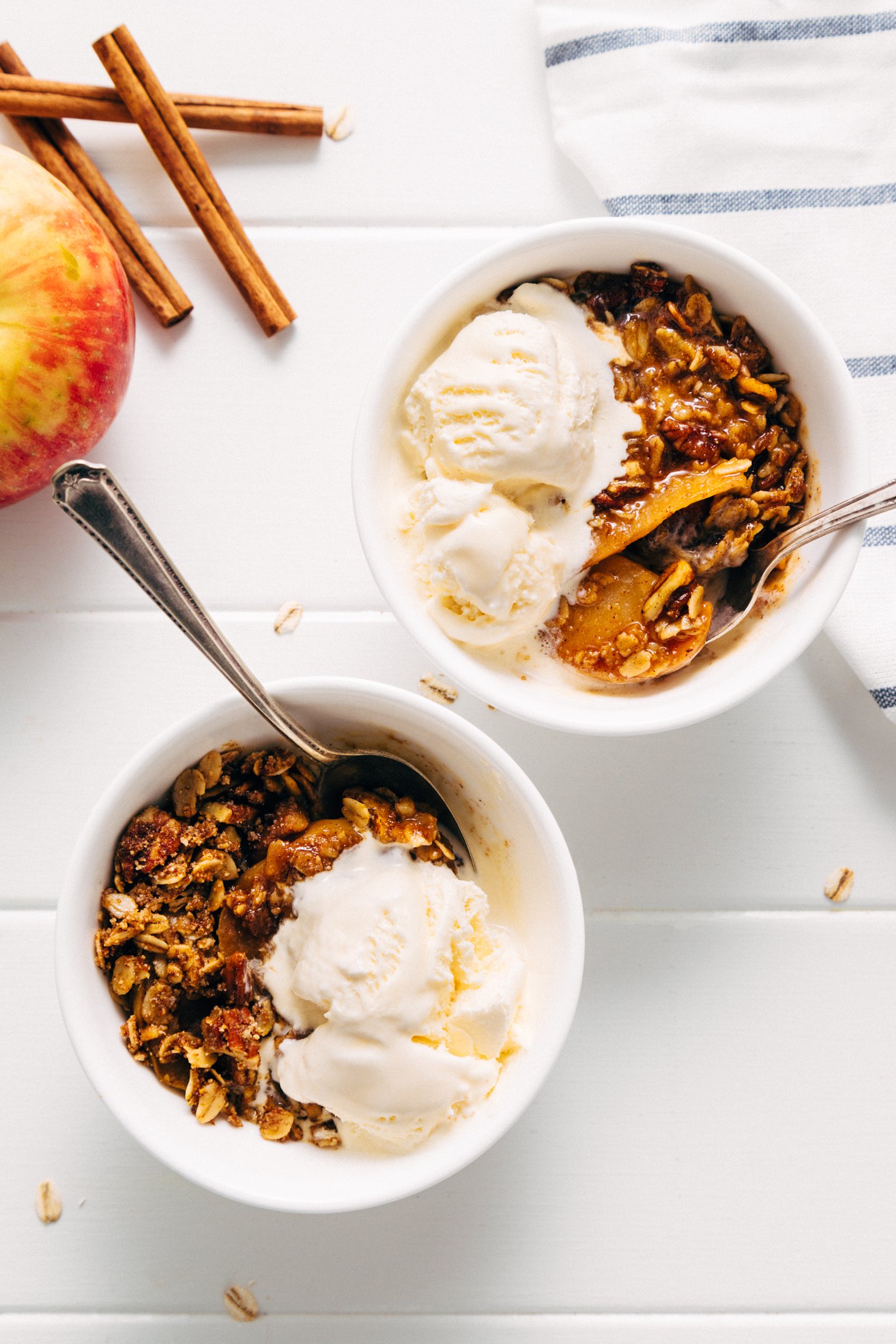 Two bowls of gluten-free vegan Apple Crisp topped with scoops of vanilla ice cream
