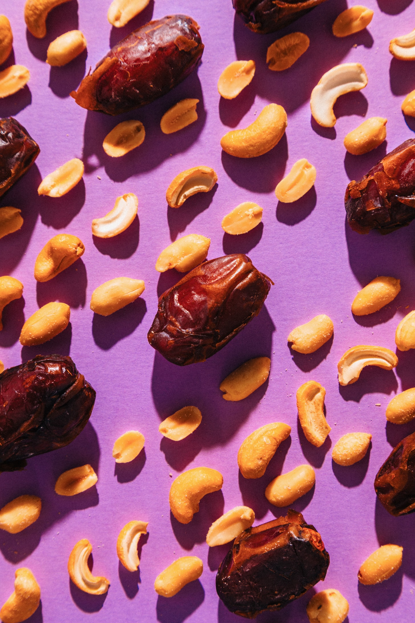 Dates, cashews, and peanuts on a purple background for making our PayDay Candy Bar Recipe