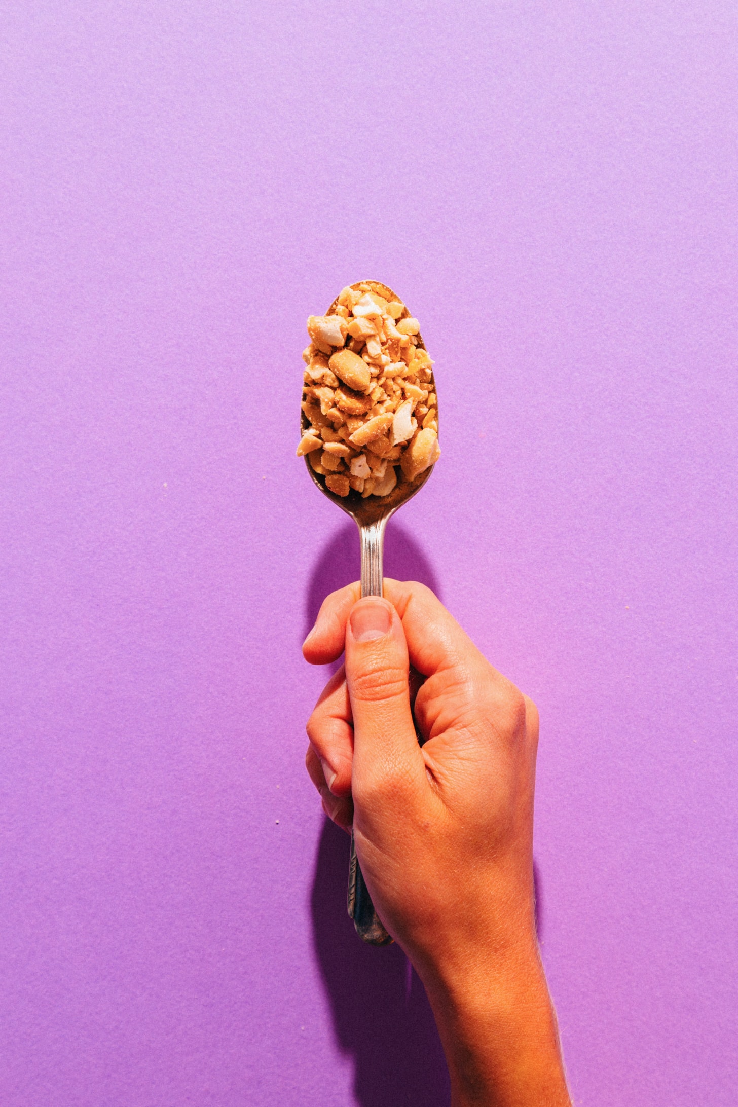 Spoonful of crushed peanuts and cashews for making homemade PayDay Bars