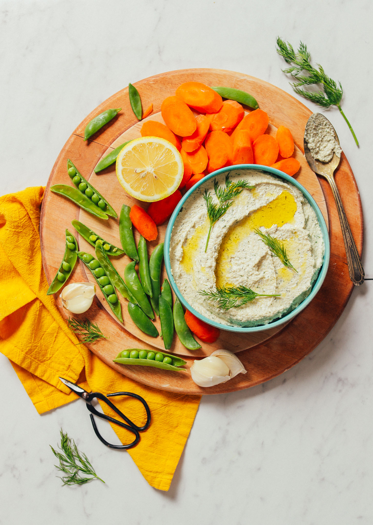 Wood cutting board with fresh vegetables and a bowl of Garlic Dill Sunflower Dip