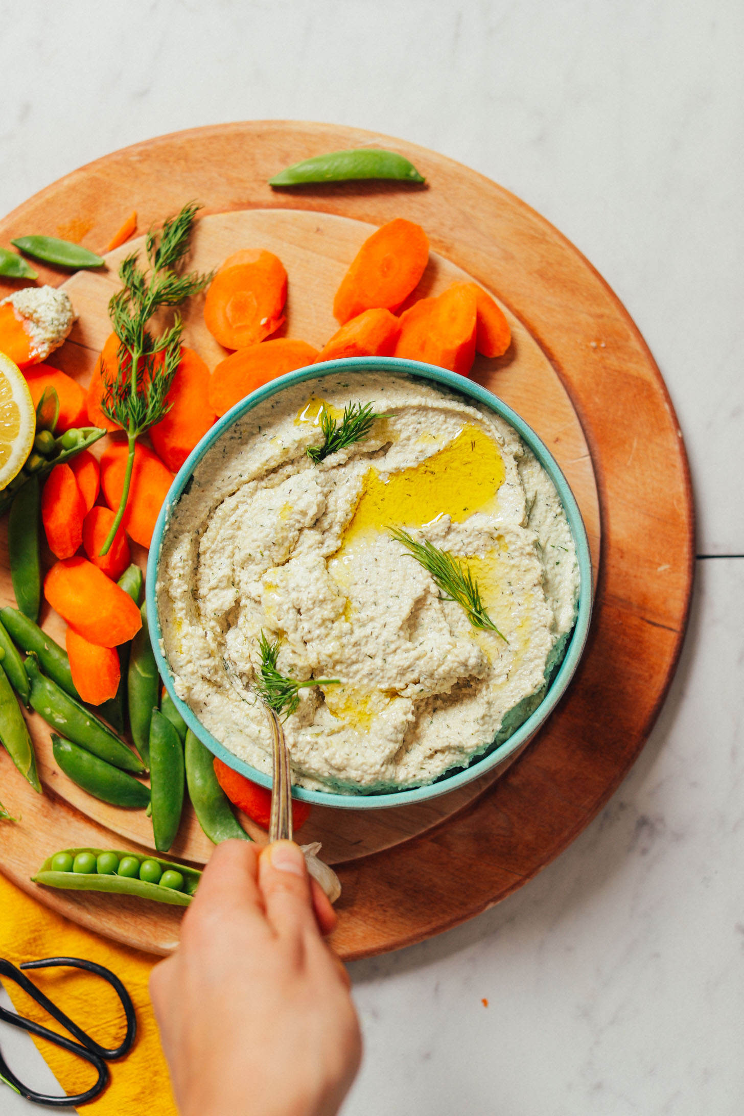 Using a spoon to scoop up Garlic Dill Sunflower Dip for serving on vegetables