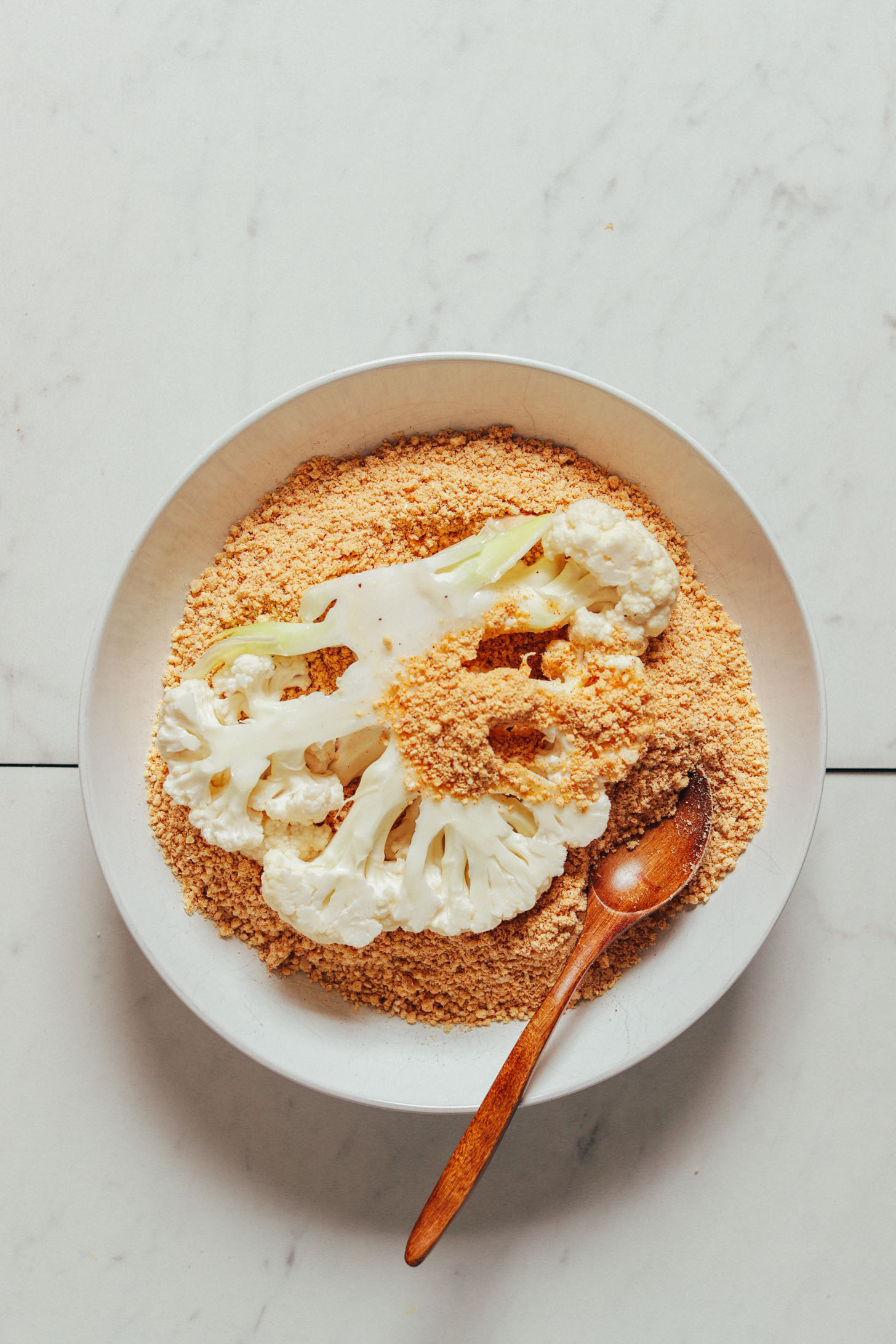 Cauliflower steak in a bowl of cashew breading