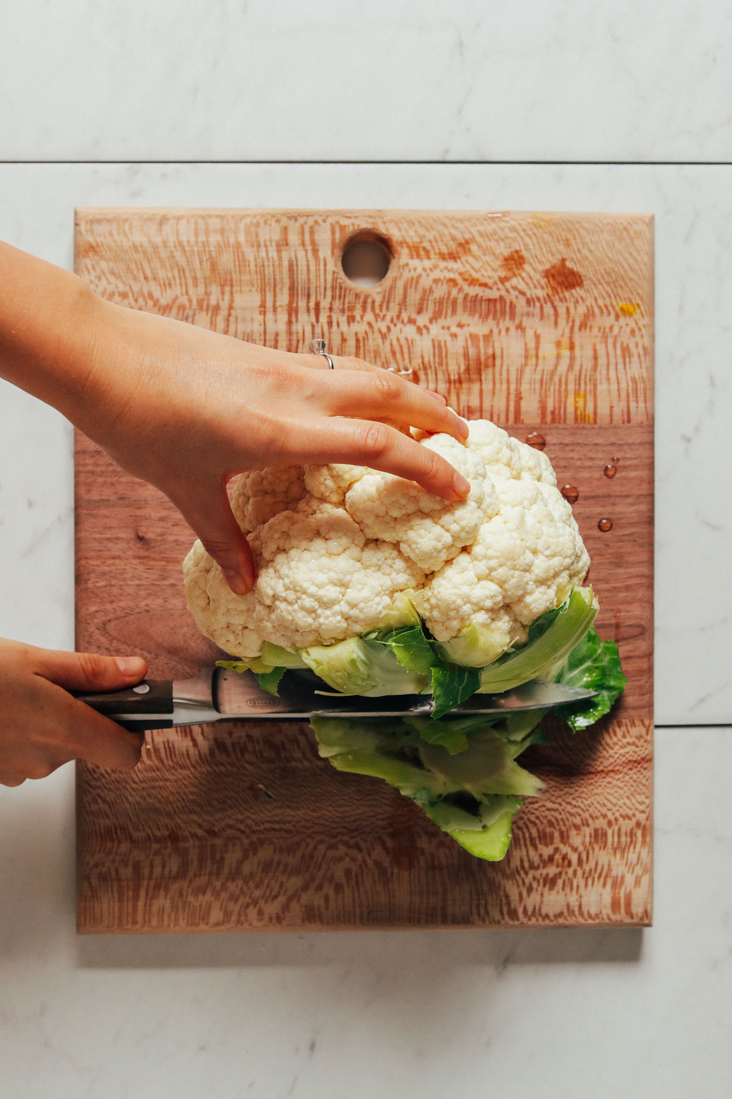 Slicing the stalky portion off a head of cauliflower