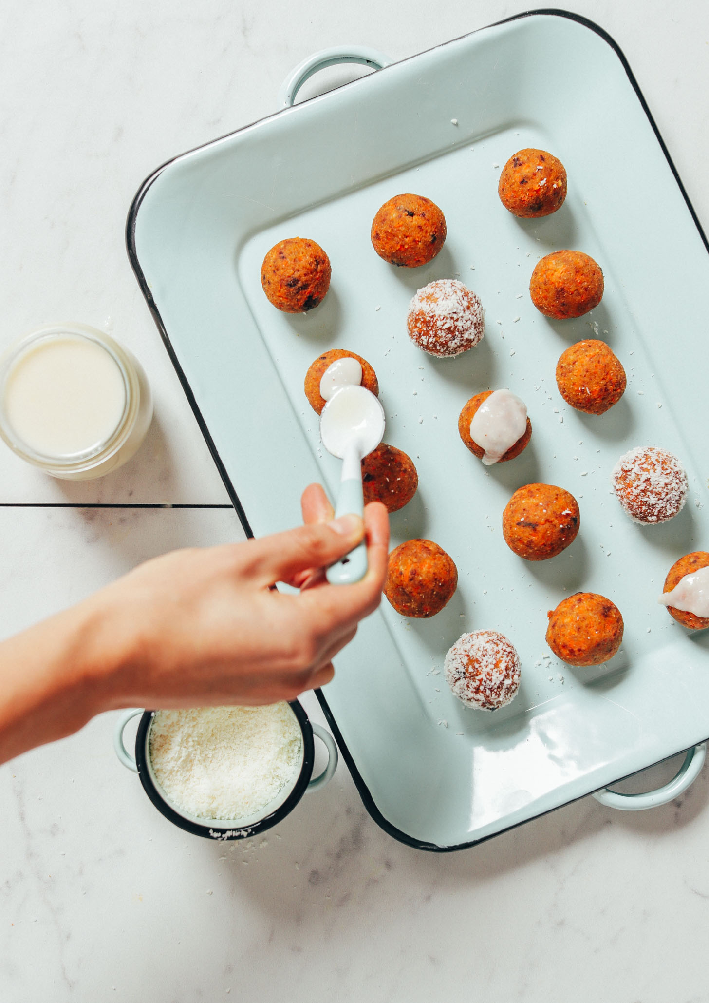 Using a spoon to spread coconut icing onto a Raw Carrot Cake Bite