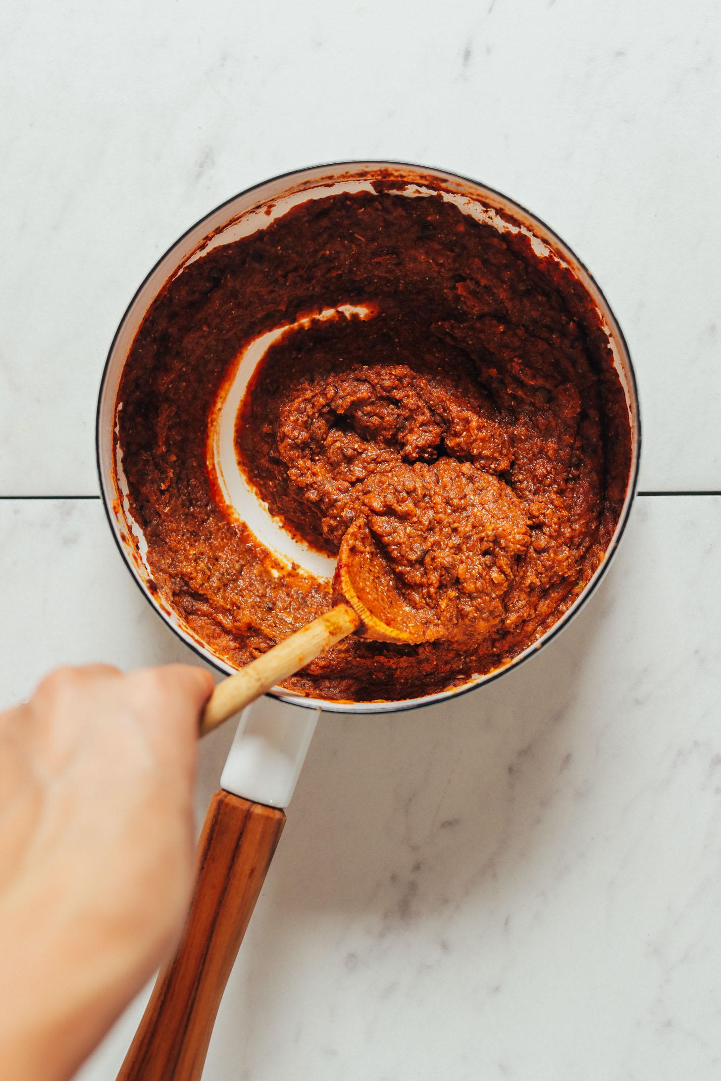 Using a wooden spoon to scoop up Smoky Refried Lentils