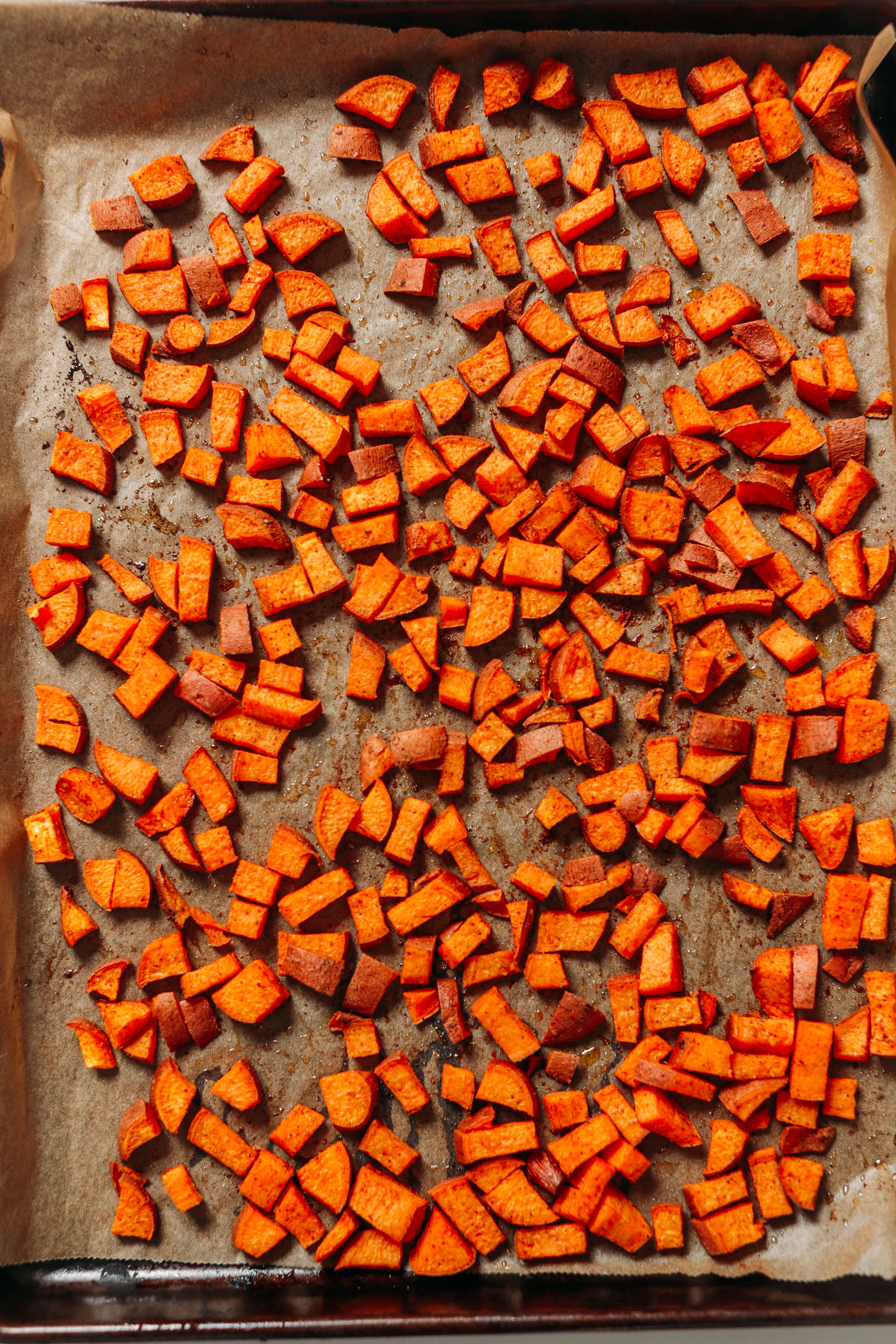 Cubed roasted sweet potatoes on a parchment-lined baking sheet