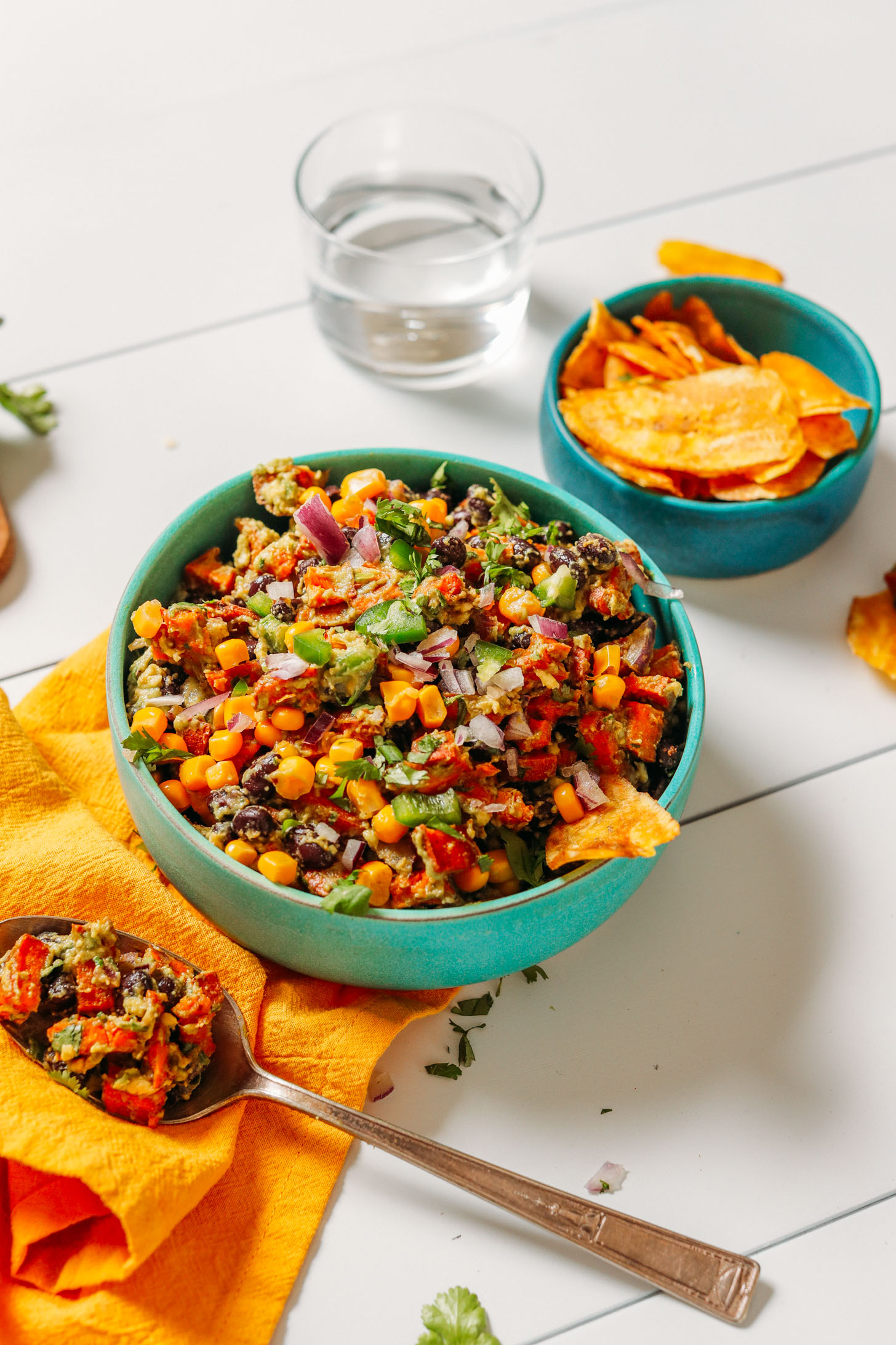 Glass of water, plantain chips, and a bowl of Southwest Sweet Potato Black Bean Dip