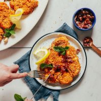 Using a fork and knife to cut into a Cashew Cauliflower Steak topped with dates and mint