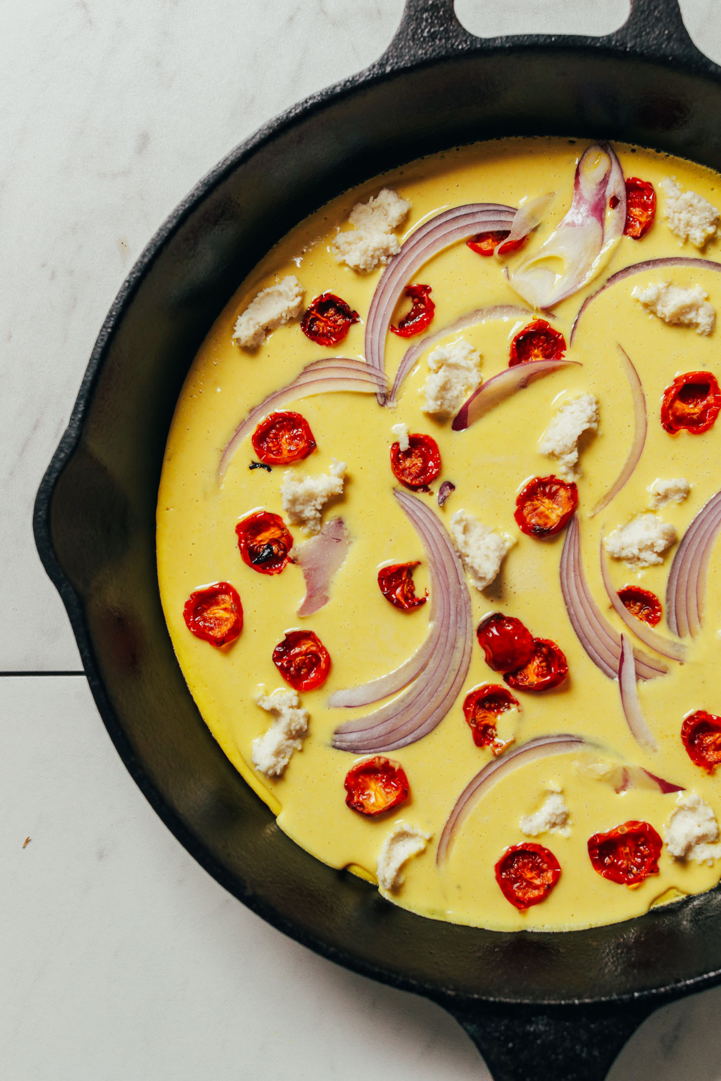 Cast-iron skillet filled with Vegan Frittata made with red onion, slow roasted tomatoes, and vegan ricotta