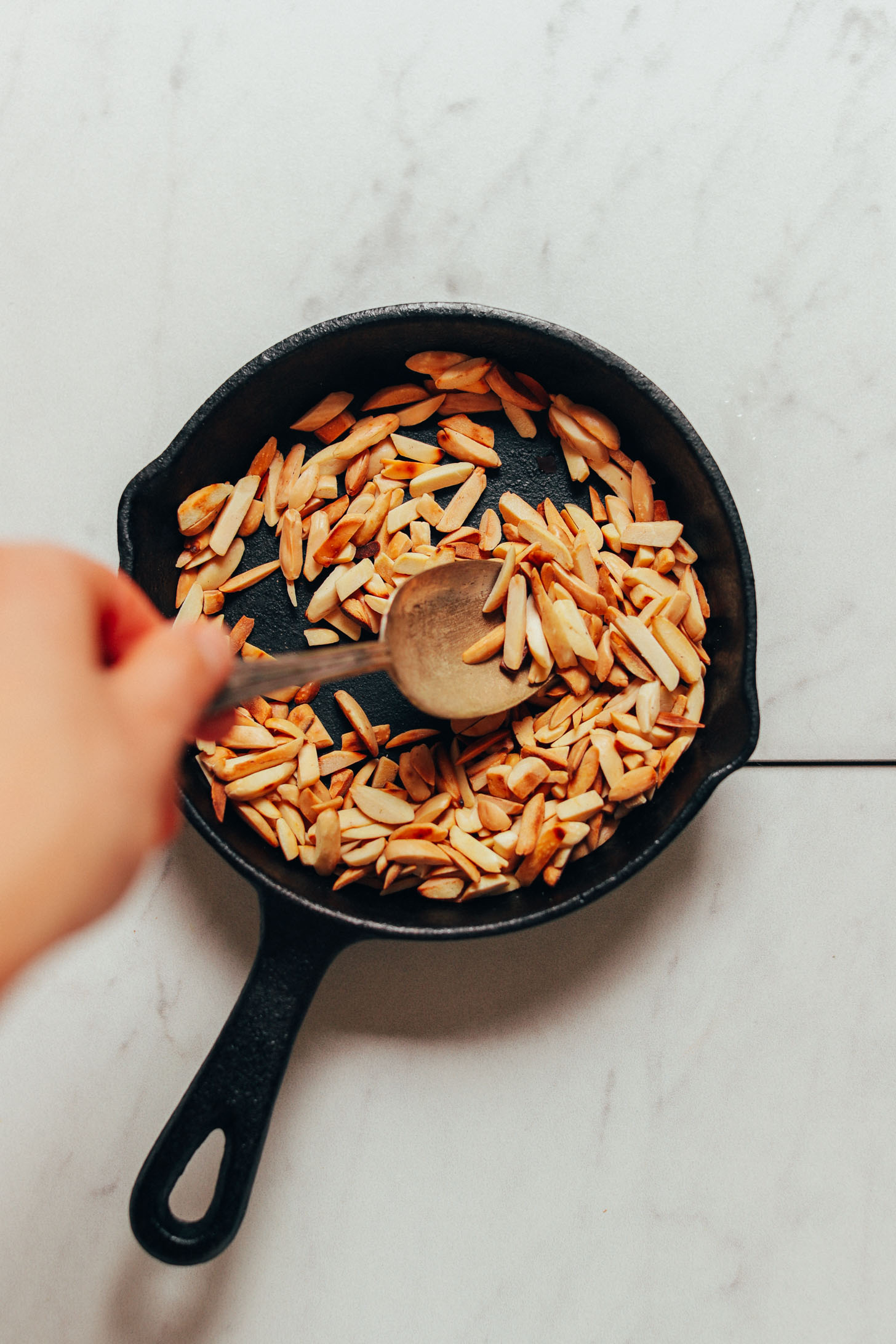 Toasted slivered almonds in a cast iron skillet for making Romesco Sauce