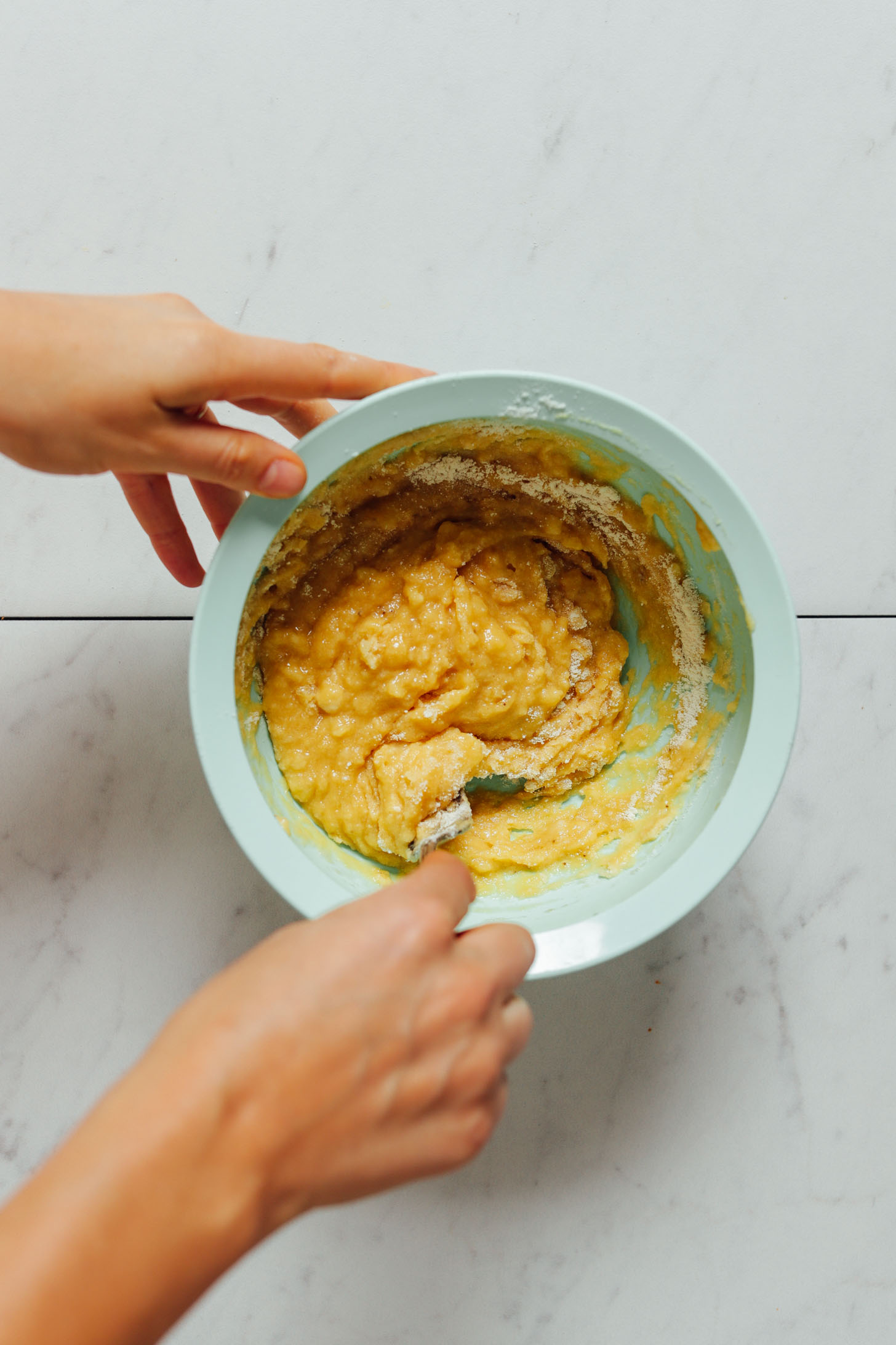 Using a fork to mix a bowl of Banana Pancake batter