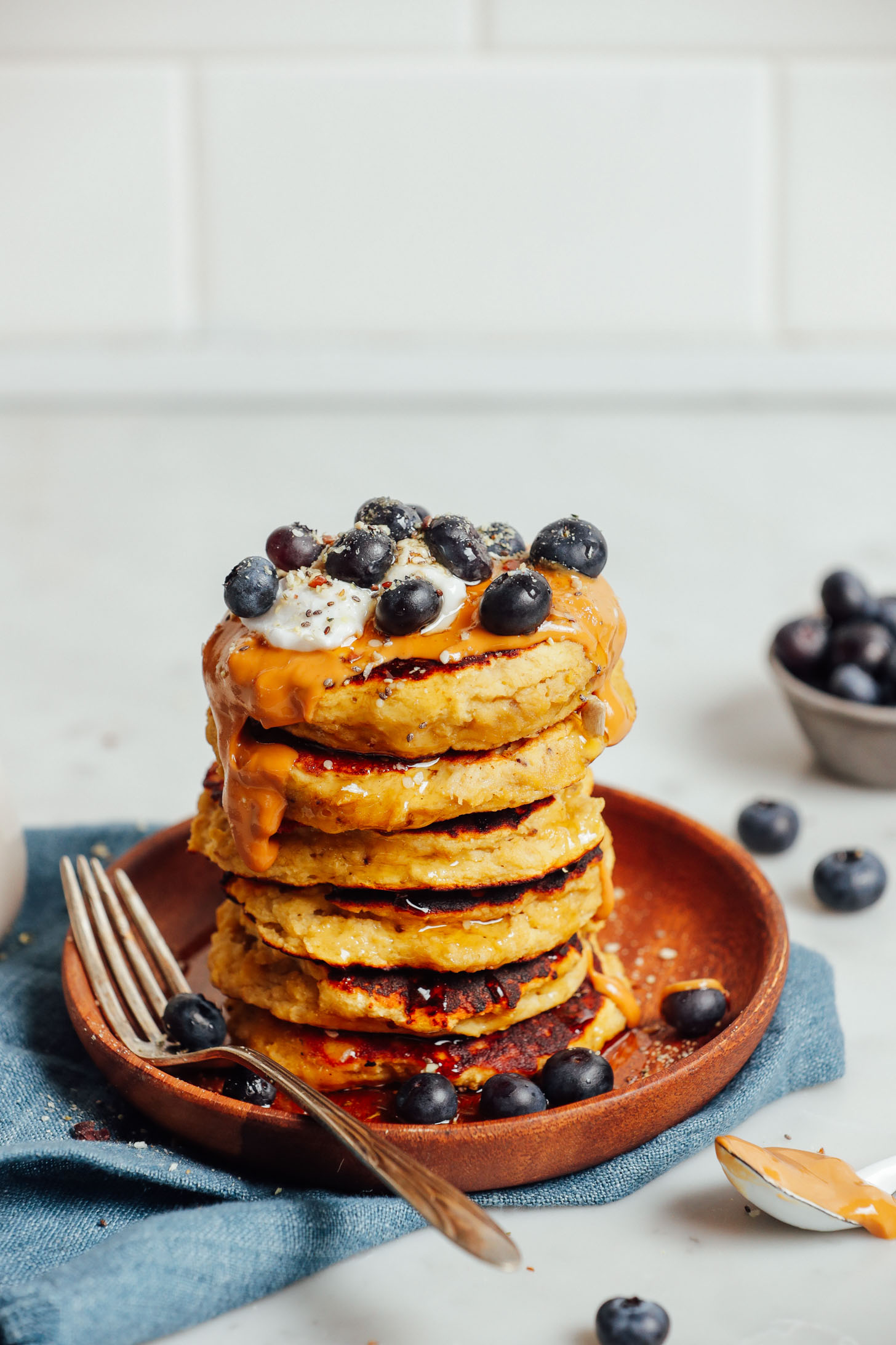Stack of Banana Pancakes topped with peanut butter, coconut yogurt, and fresh blueberries