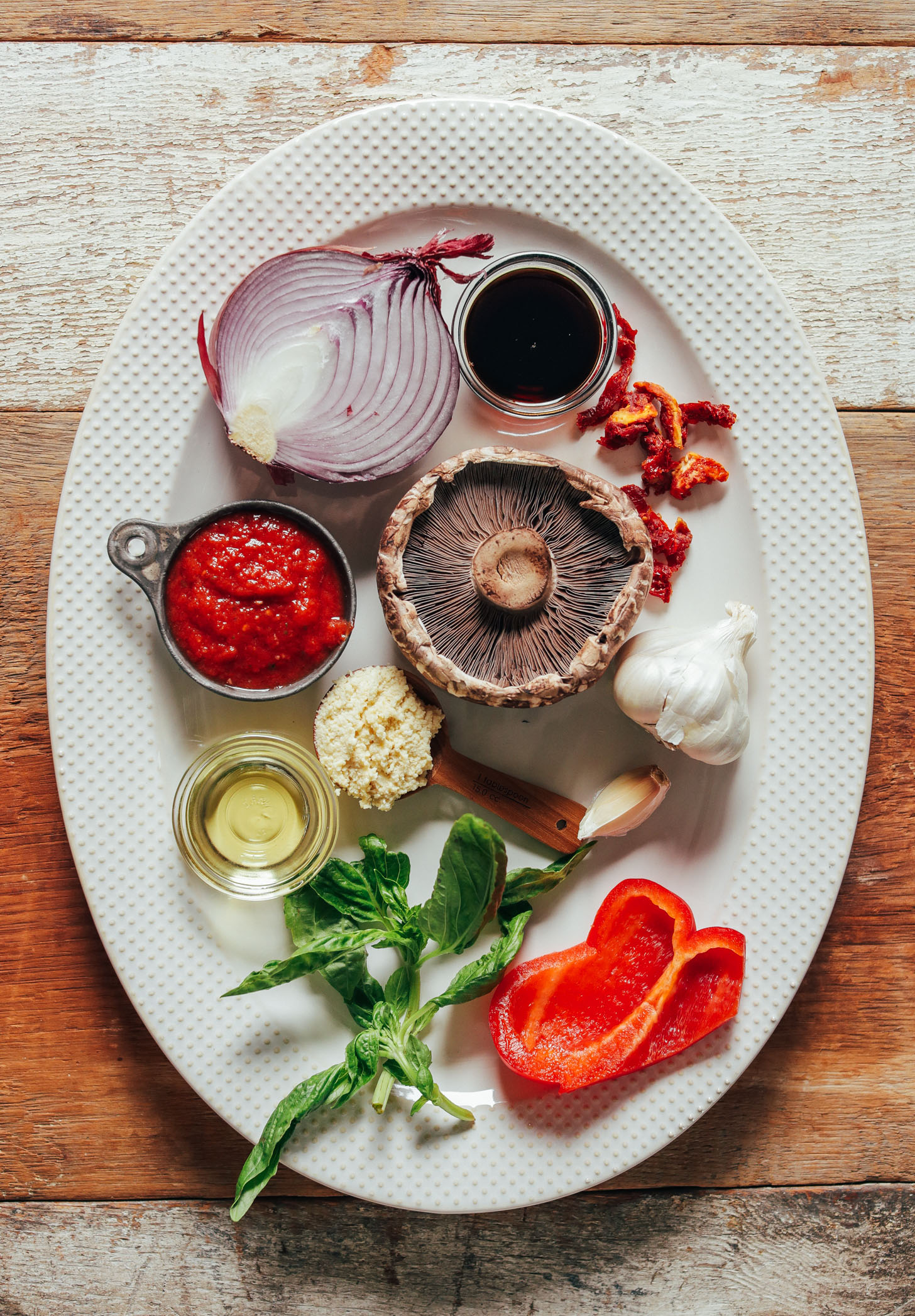 Large white ceramic platter filled with ingredients for making our Balsamic-Marinated Portobello Pizzas recipe