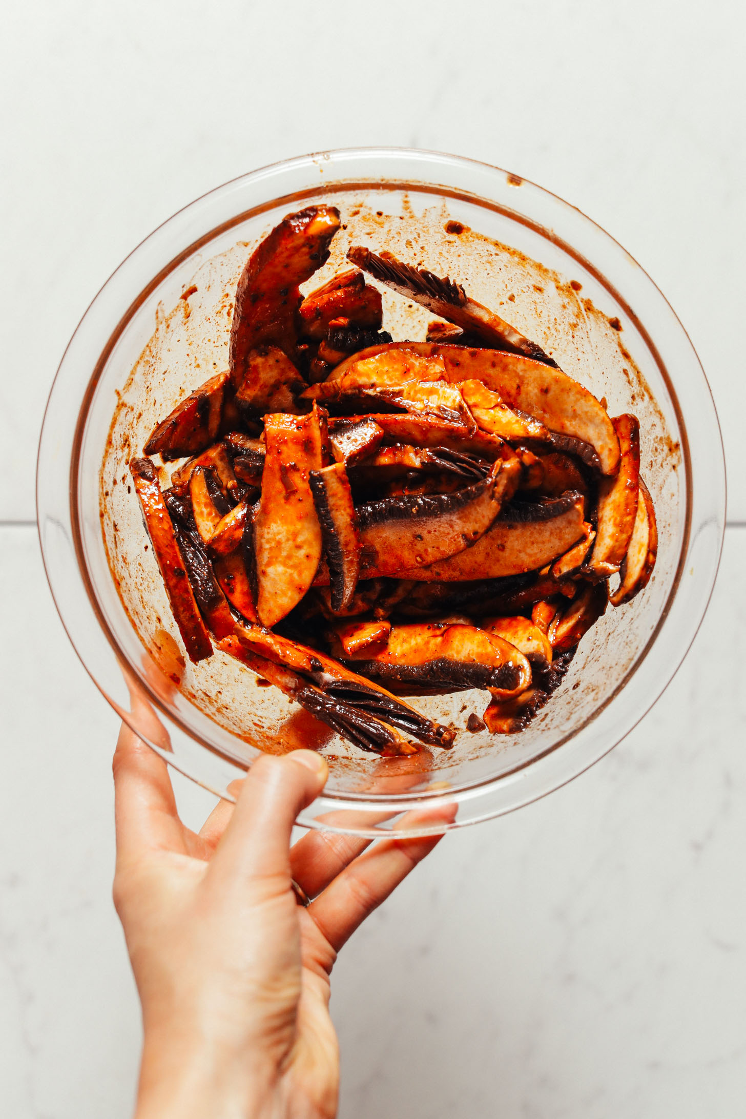 Bowl of portobello mushroom slices coated in seasonings for our Portobello Bacon recipe