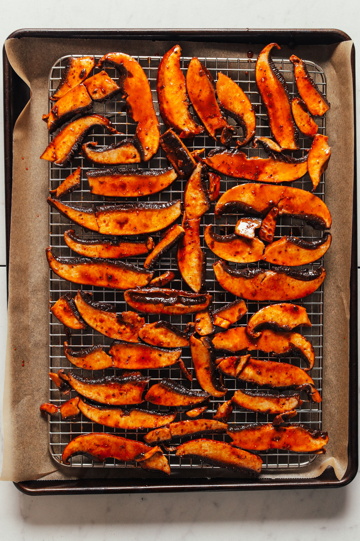 Parchment-lined baking sheet topped with a cooling rack filled with Vegan Portobello Bacon