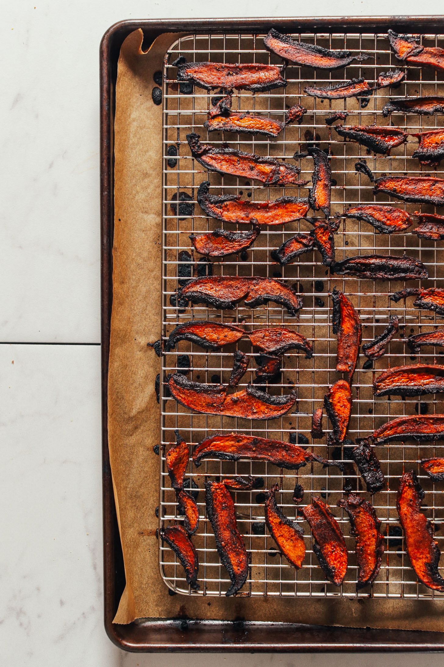 Fresh from the oven Portobello Bacon on a cooling rack over a parchment-lined baking sheet