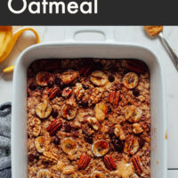 Hands holding a baking dish of vegan and gluten-free chocolate chip banana baked oatmeal