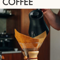 Hand pouring a water from a gooseneck kettle into a chemex coffee maker