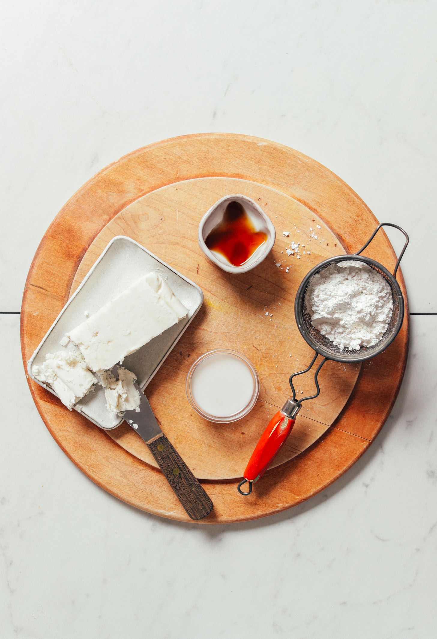 Cutting board with vegan butter, vanilla, powdered sugar, and coconut milk for making vegan frosting