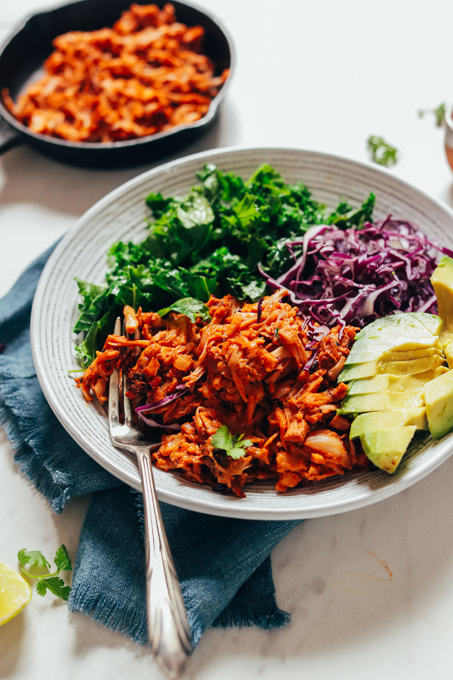 Fork resting on a bowl of Smoky Marinated Jackfruit with fresh vegetables