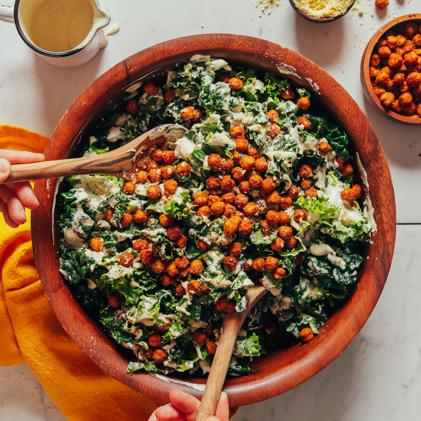 Using salad tongs to pick up a serving of our delicious Kale Caesar Salad with Crispy Chickpeas