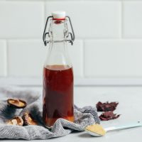 straight on shot of vegetarian fish sauce in a clear bottle with mushrooms on the side