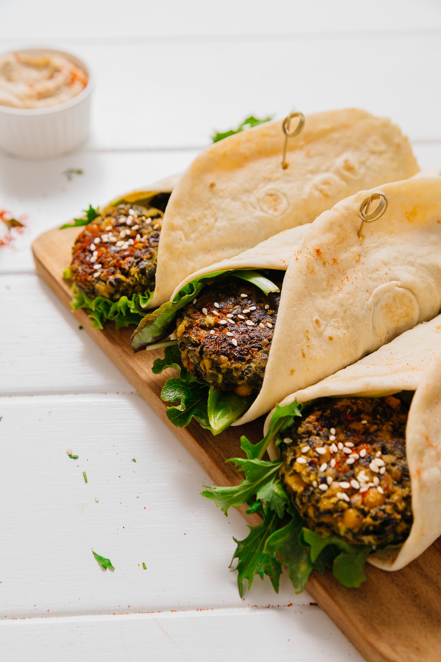 Cutting board with Kale Falafel Hummus Wraps made with pita bread and fresh greens