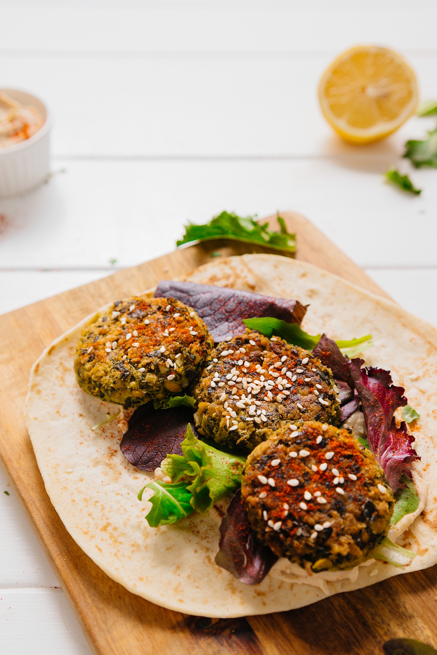 Cutting board with pita bread topped with greens and falafel made with kale