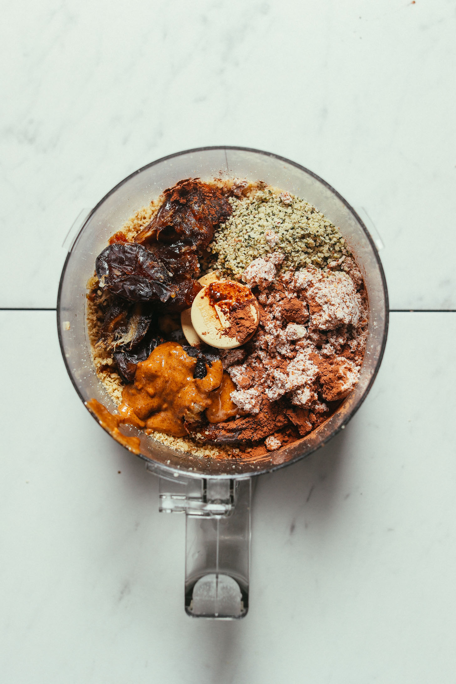 Food processor filled with ingredients for making Almond Pulp Brownie Bliss Balls