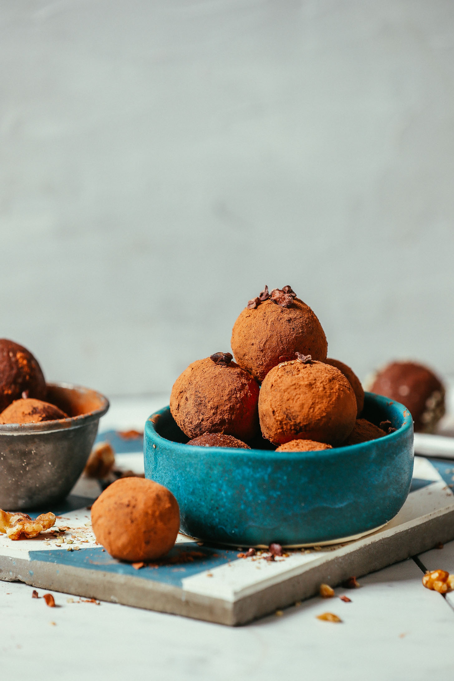 Measuring cup and bowl filled with Brownie Bliss Balls coated in cacao powder