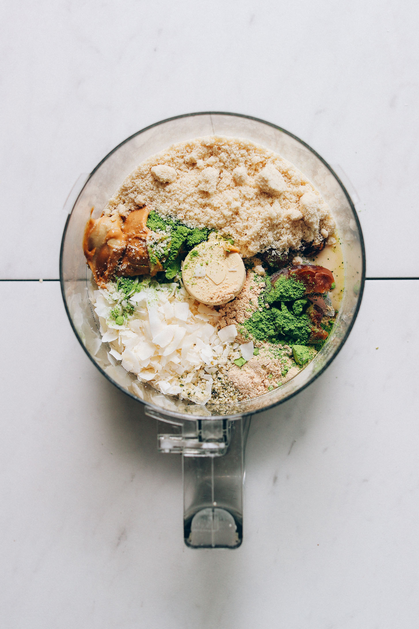 Food processor filled with ingredients for making date-sweetened Matcha Bliss Balls