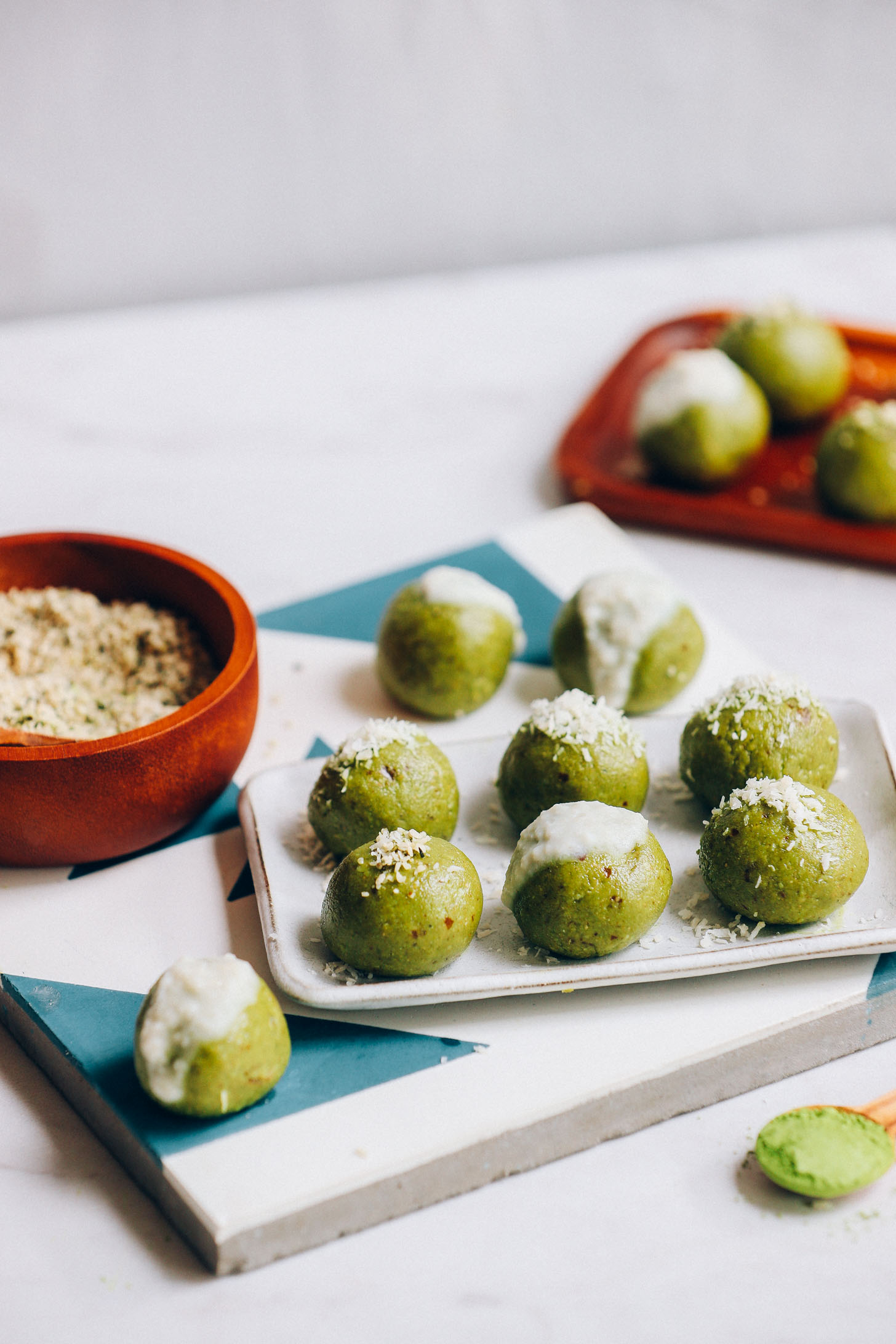 Plate of Matcha Bliss Balls topped with coconut butter icing and hemp seeds