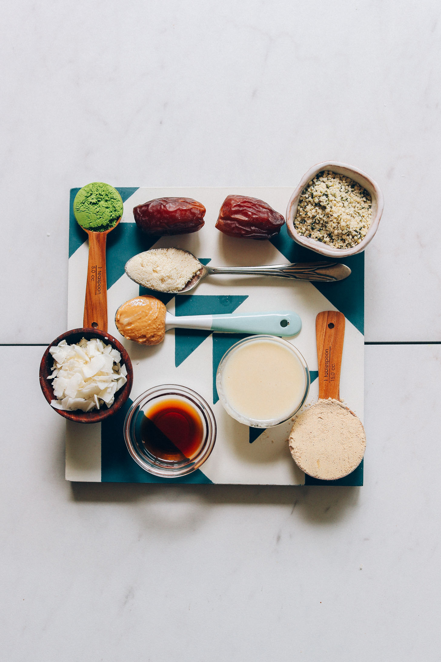 Blue and white tile topped with ingredients for making Matcha Bliss Balls