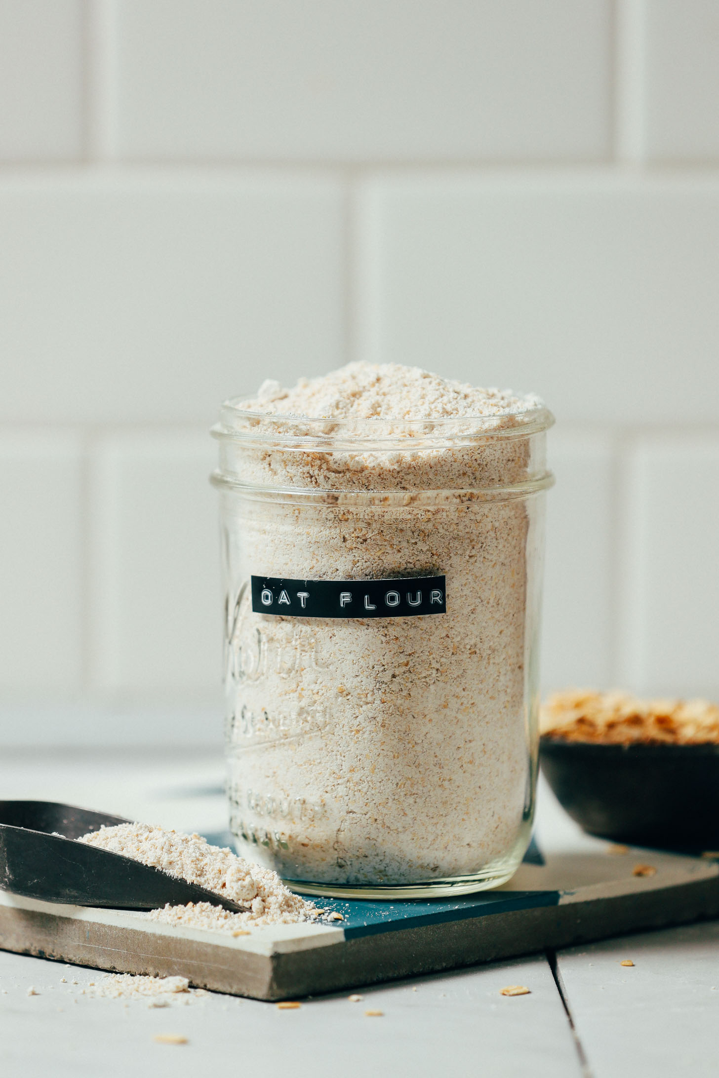 Scoop and jar of homemade oat flour made with our DIY Tutorial on How to Make Oat Flour