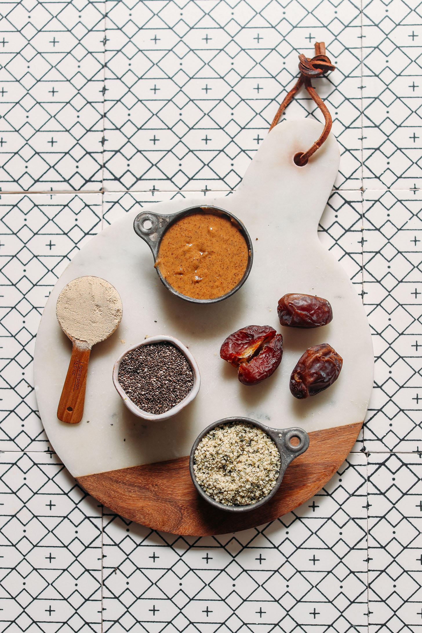 Cutting board with almond butter, dates, hemp seeds, chia seeds, and protein powder for making Protein Balls